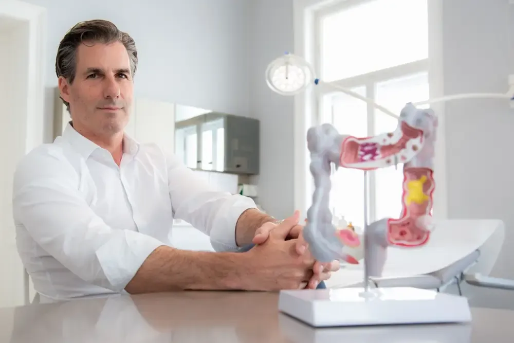 Priv. Doz. Dr. Emanuel Sporn in seiner Ordination neben einem anatomischen Darmmodell